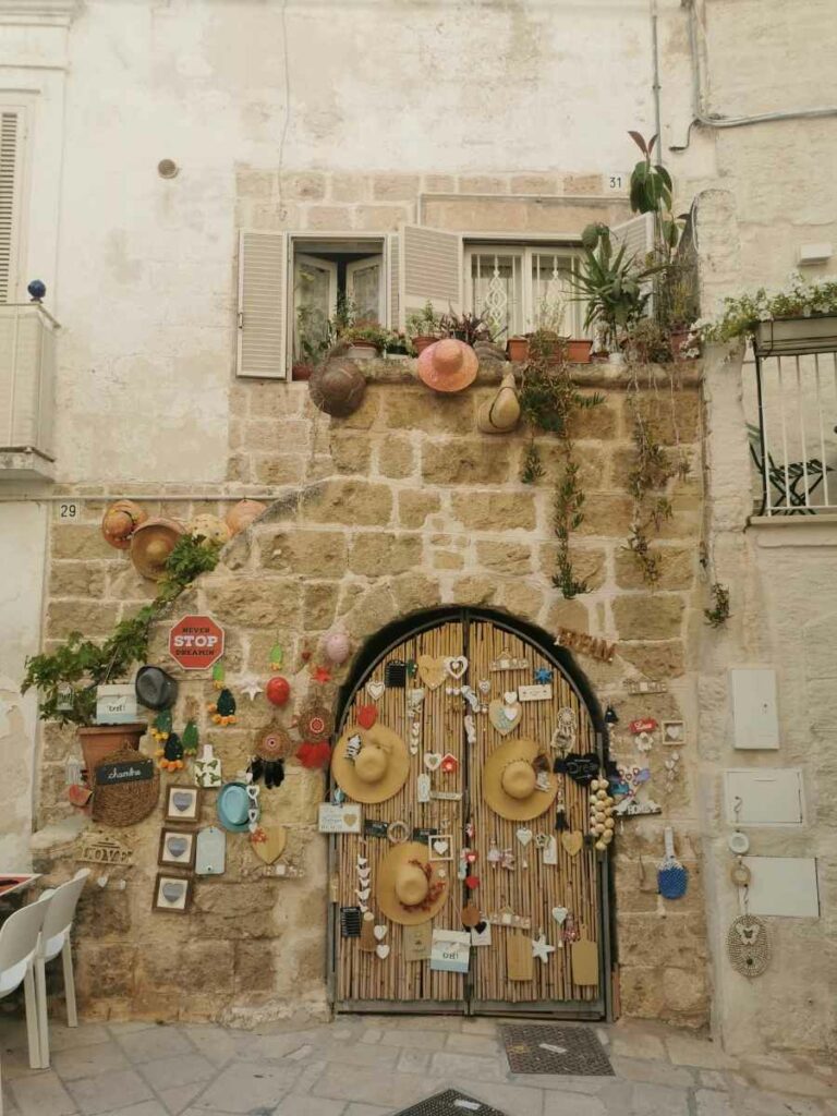 porta decorata con cappelli e altri oggetti nel centro storico di polignano a mare