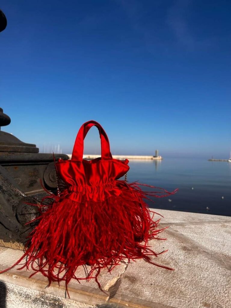 borsa rossa con piume sul lungomare